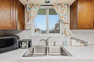 Kitchen with light countertops, brown cabinets, and black microwave