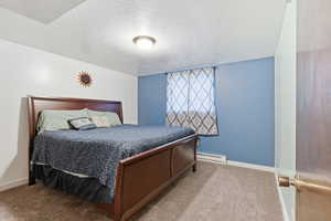 Bedroom featuring carpet, a textured ceiling, and baseboard heating
