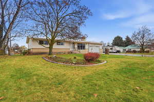 Back of house with a chimney, brick siding, an attached garage, and driveway