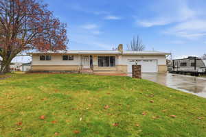 Single story home with brick siding, a chimney, driveway, and an attached garage
