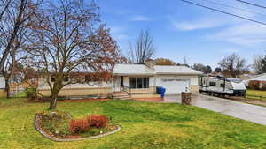 Single story home with a metal roof, a chimney, driveway, a front lawn, and a garage