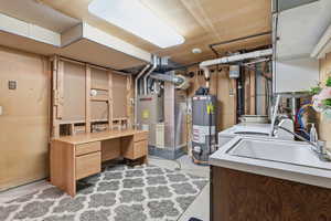 Unfinished basement with water heater, heating unit, and washer / clothes dryer