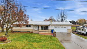 Single story home with a metal roof, a chimney, concrete driveway, and a garage