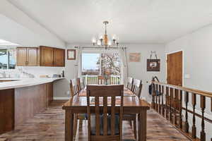 Dining area with dark wood-style floors, a chandelier, and a textured ceiling
