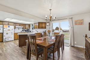 Dining space with a chandelier, a textured ceiling, and light wood finished floors