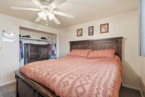 Bedroom with dark colored carpet, a closet, and ceiling fan