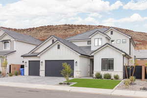 Modern inspired farmhouse with board and batten siding, stone siding, decorative driveway, and a garage