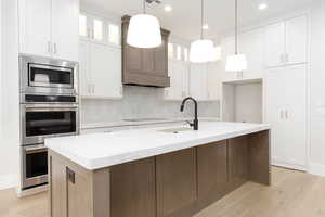 Kitchen with tasteful backsplash, light wood-type flooring, light stone countertops, and recessed lighting