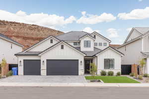 Modern farmhouse with board and batten siding, decorative driveway, a garage, a tile roof, and stone siding