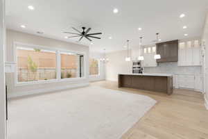 Kitchen with white cabinetry, glass insert cabinets, open floor plan, decorative backsplash, and decorative light fixtures
