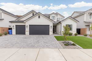 Modern farmhouse featuring decorative driveway, board and batten siding, stone siding, and a garage