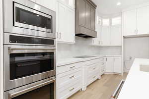 Kitchen featuring light stone counters, decorative backsplash, and white cabinets