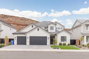 Modern farmhouse featuring board and batten siding, decorative driveway, an attached garage, stone siding, and a tiled roof