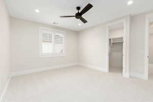Unfurnished bedroom featuring a spacious closet, light carpet, recessed lighting, and a ceiling fan