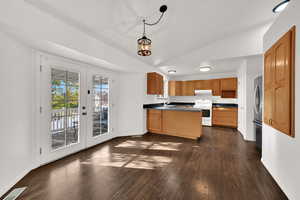 Kitchen with french doors, dark wood-style floors, white range with electric stovetop, decorative light fixtures, and vaulted ceiling