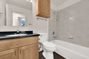 Full bathroom with shower / bathtub combination, vanity, and dark wood-type flooring