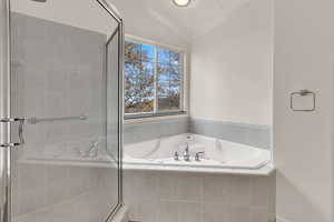 Bathroom featuring a jetted tub, a stall shower, and vaulted ceiling