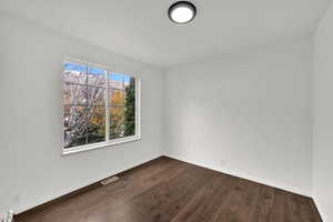 Empty room featuring baseboards and dark wood-style flooring