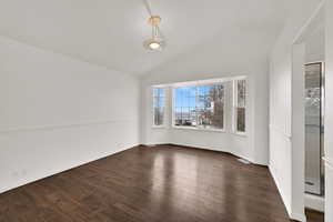 Unfurnished room featuring lofted ceiling and dark wood-style flooring