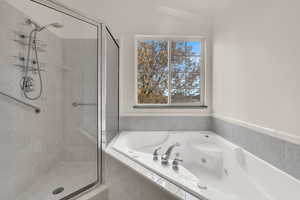 Bathroom featuring a jetted tub, a shower stall, and vaulted ceiling