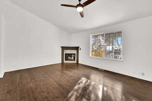 Unfurnished living room with vaulted ceiling, a premium fireplace, dark wood finished floors, and a ceiling fan