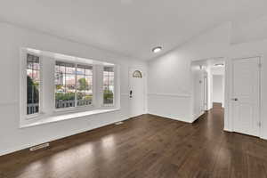Spare room with vaulted ceiling and dark wood-style floors