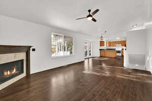 Unfurnished living room featuring lofted ceiling, ceiling fan, dark wood-style flooring, french doors, and a tile fireplace