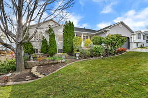 View of front of property featuring a front yard, stucco siding, a garage, and driveway