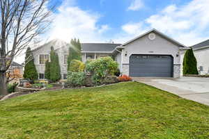Single story home featuring a front yard, driveway, stucco siding, and a garage