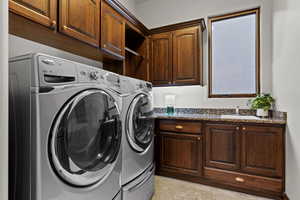 Laundry area with cabinet space, washing machine and clothes dryer, and light tile patterned floors