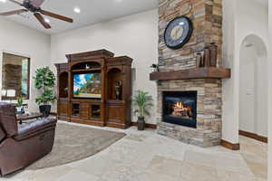 Living room featuring a stone fireplace, a ceiling fan, and recessed lighting