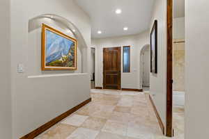 Hallway with arched walkways, recessed lighting, and light tile patterned flooring