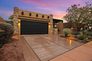 View of front of property featuring concrete driveway, stucco siding, stone siding, and an attached garage