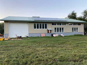 Rear view of 50 x 80 barn featuring solar panels, a lawn,  and a metal roof