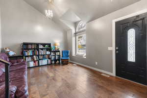 Foyer featuring wood-type flooring, a chandelier, and vaulted ceiling