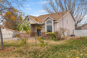 View of front facade featuring roof with shingles, brick siding, and a gate