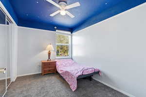 Bedroom with carpet, a closet, a ceiling fan, and a textured ceiling