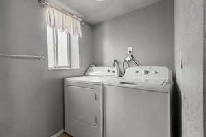 Laundry area featuring a textured wall and independent washer and dryer