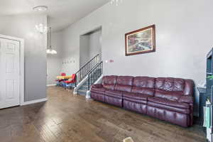 Living area featuring stairway, lofted ceiling, dark wood-style flooring, and a chandelier