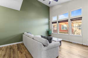 Living area featuring light wood-style flooring, a ceiling fan, and a high ceiling