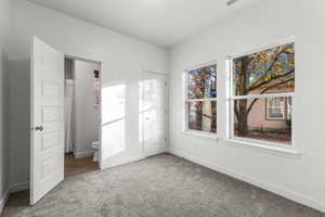 Unfurnished bedroom with carpet flooring and connected bathroom