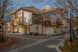 View of front of home featuring stucco siding, a balcony, and a garage