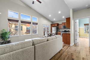 Living room with light wood-type flooring, ceiling fan, recessed lighting, high vaulted ceiling, and french doors