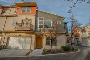 Traditional-style house with a balcony, stucco siding, concrete driveway, and a garage