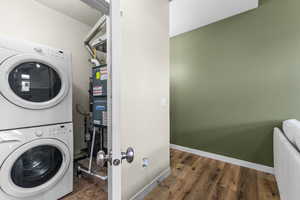 Laundry area featuring stacked washer / drying machine and dark wood-style floors