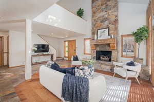 Living room featuring plenty of natural light, high vaulted ceiling, wood finished floors, and a fireplace