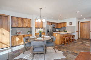 Dining room featuring recessed lighting, a chandelier, and stone tile floors