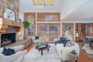 Living room featuring a towering ceiling, a fireplace, and wood finished floors