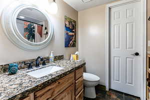 Bathroom with vanity, a shower with curtain, and dark stone finish flooring