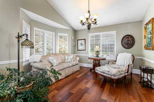 Living area featuring vaulted ceiling, dark wood-type flooring, and a chandelier